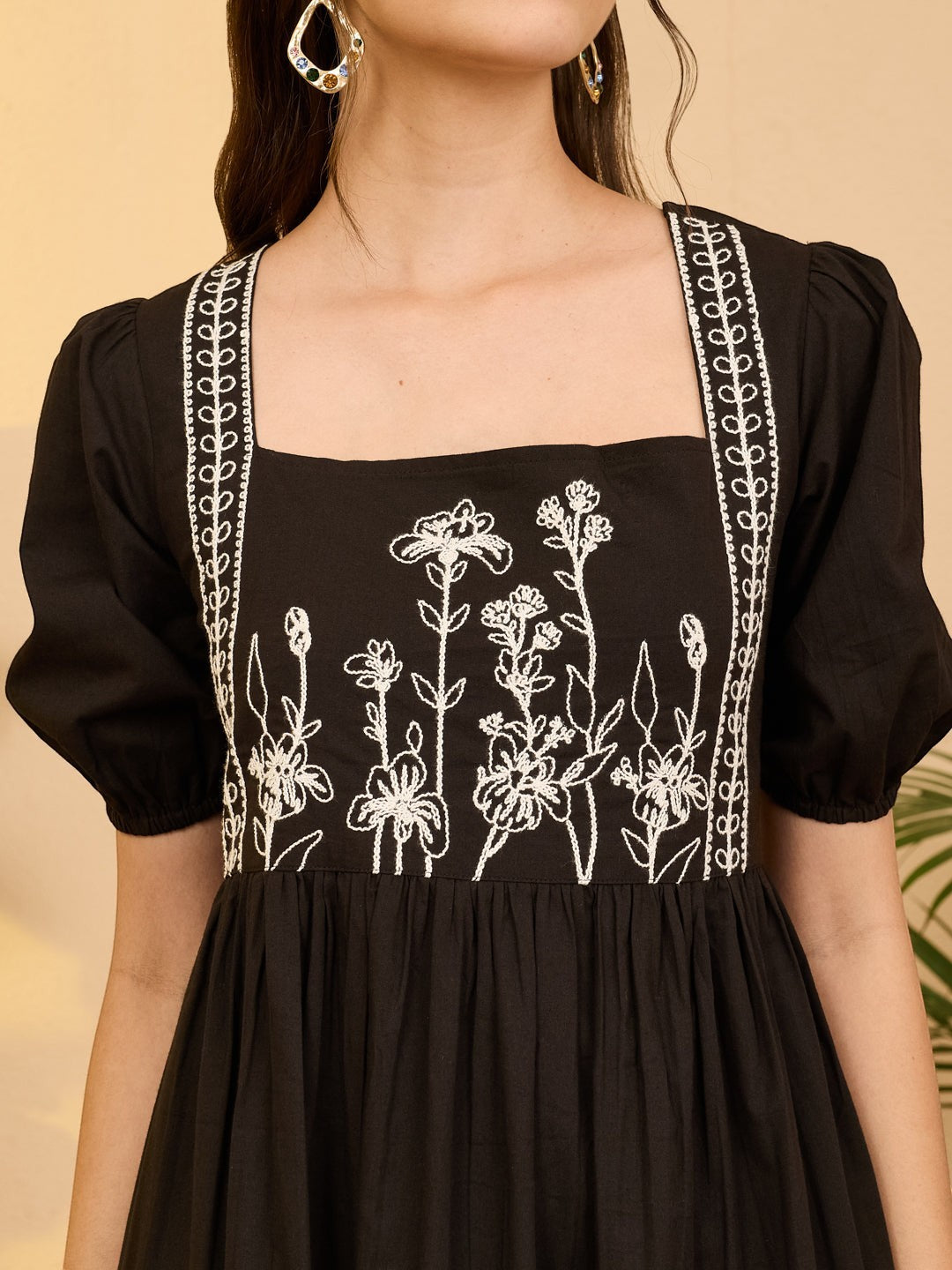 Naanu black cotton midi dress with white floral embroidery on bodice and square neckline, puff sleeves, and gathered empire waist.