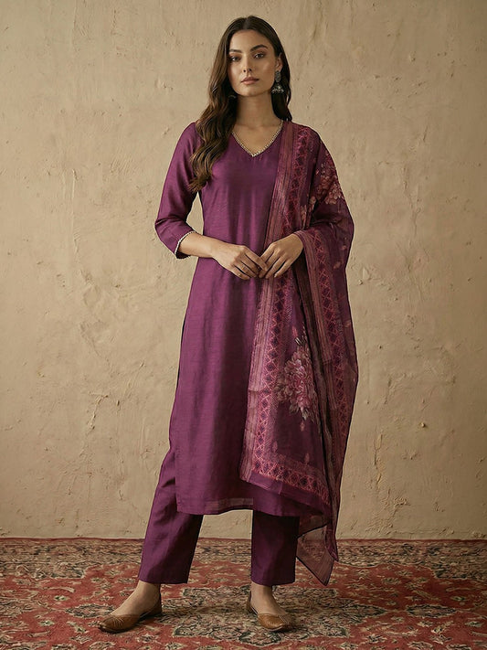 Naanu plum silk blend straight kurta set with V-neck, silver lace trim, and floral organza dupatta. Model is wearing matching pants and flats.