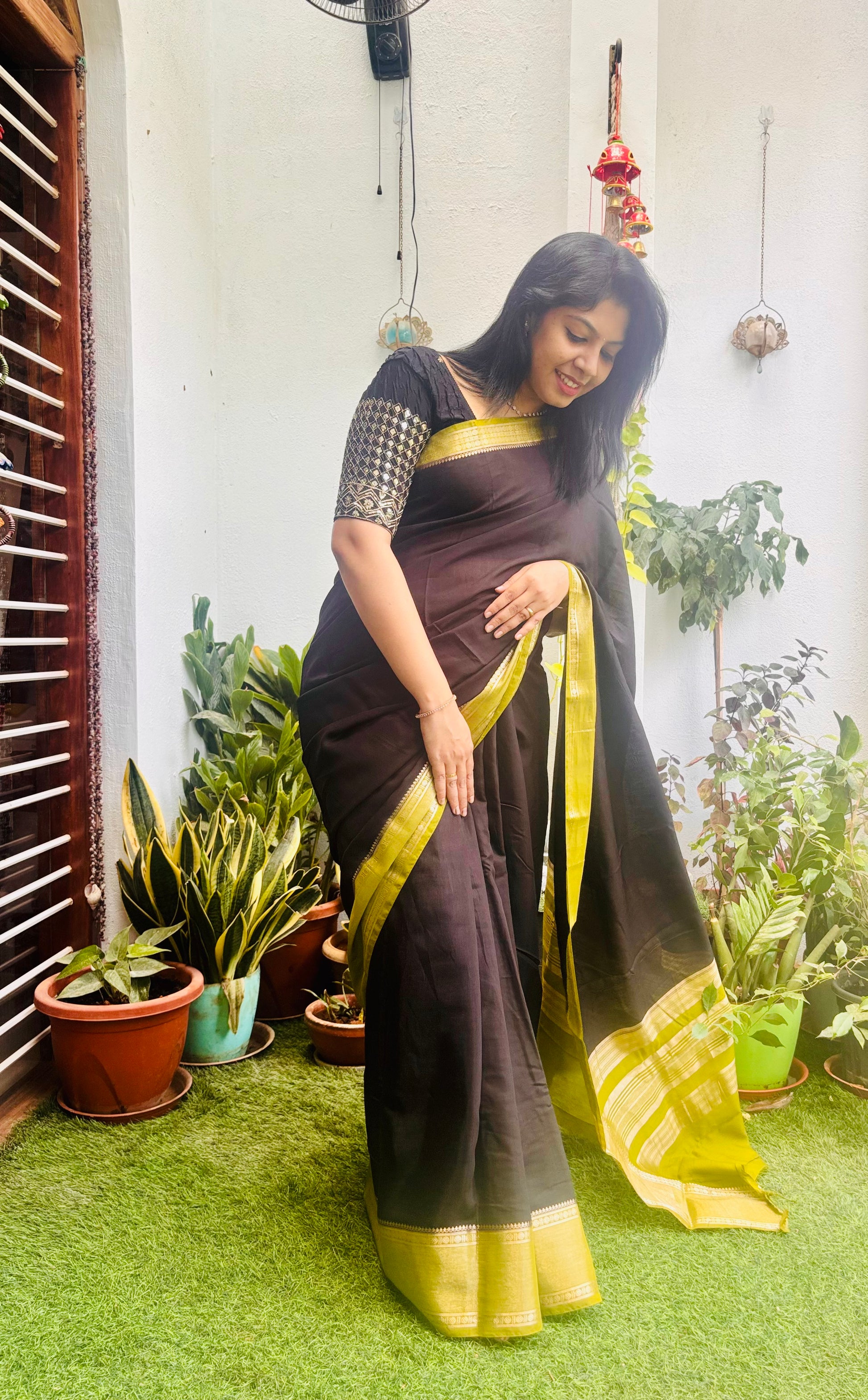 Black and green Assam silk saree - model seated reading with tea