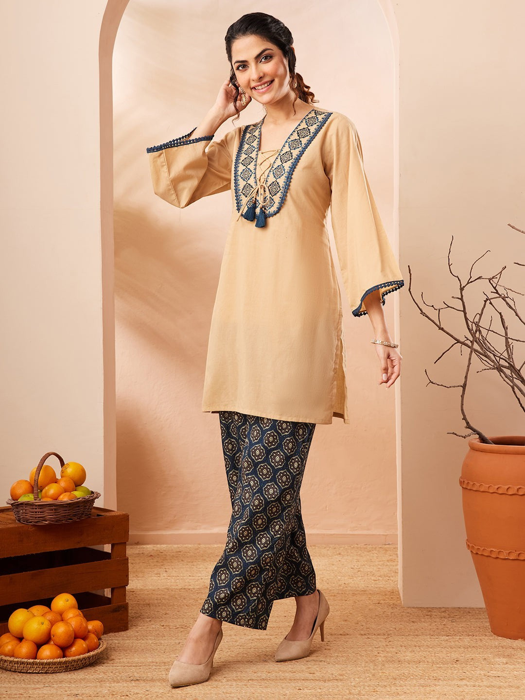 Naanu beige cotton co-ord set with embroidered V-neck, tie front, bell sleeves, and navy Ajrakh print palazzo pants.