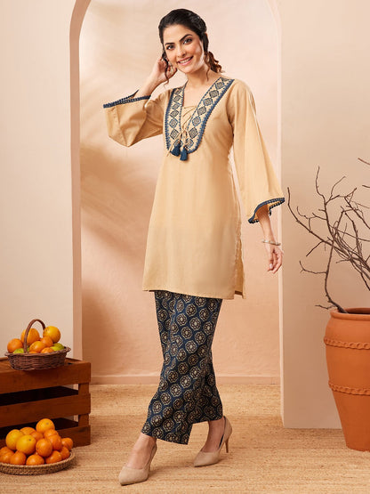 Naanu beige cotton co-ord set with embroidered V-neck, tie front, bell sleeves, and navy Ajrakh print palazzo pants.