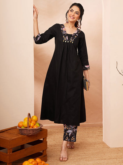 Naanu black A-line kurta with embroidered square neckline and floral print slim pants. 3/4 sleeves with embroidered cuffs.