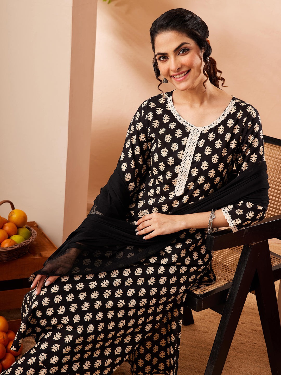 Naanu black rayon kurta set with gold leaf print, white lace trim, straight pants and black chiffon dupatta.