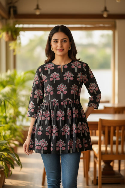 Naanu black cotton short kurti with pink, red, white lotus floral block print, gathered waist, and 3/4 sleeves.