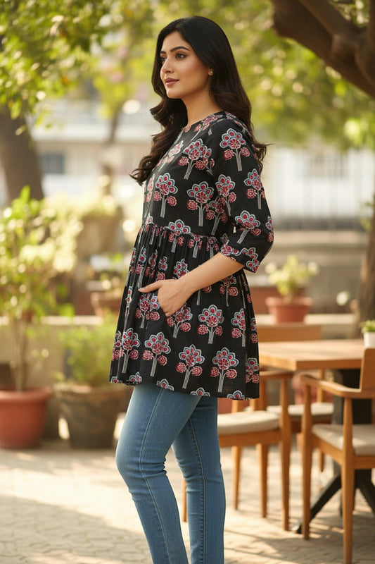 Naanu black cotton short kurti with pink, red, and white lotus floral block print, gathered waist, and 3/4 sleeves.