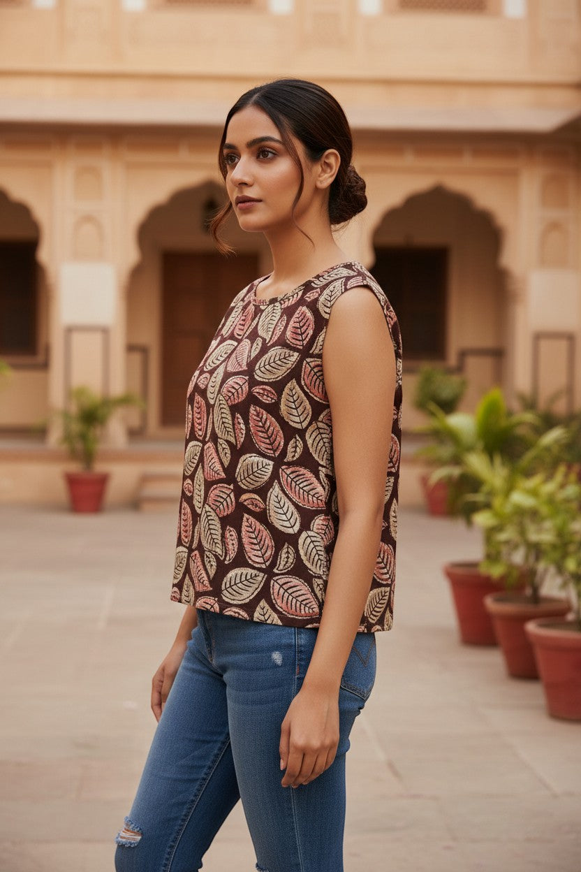 Naanu deep chocolate brown cotton top with a scattered botanical leaf print in cream, blush pink, and dusty rose. Sleeveless with a wide round neckline.