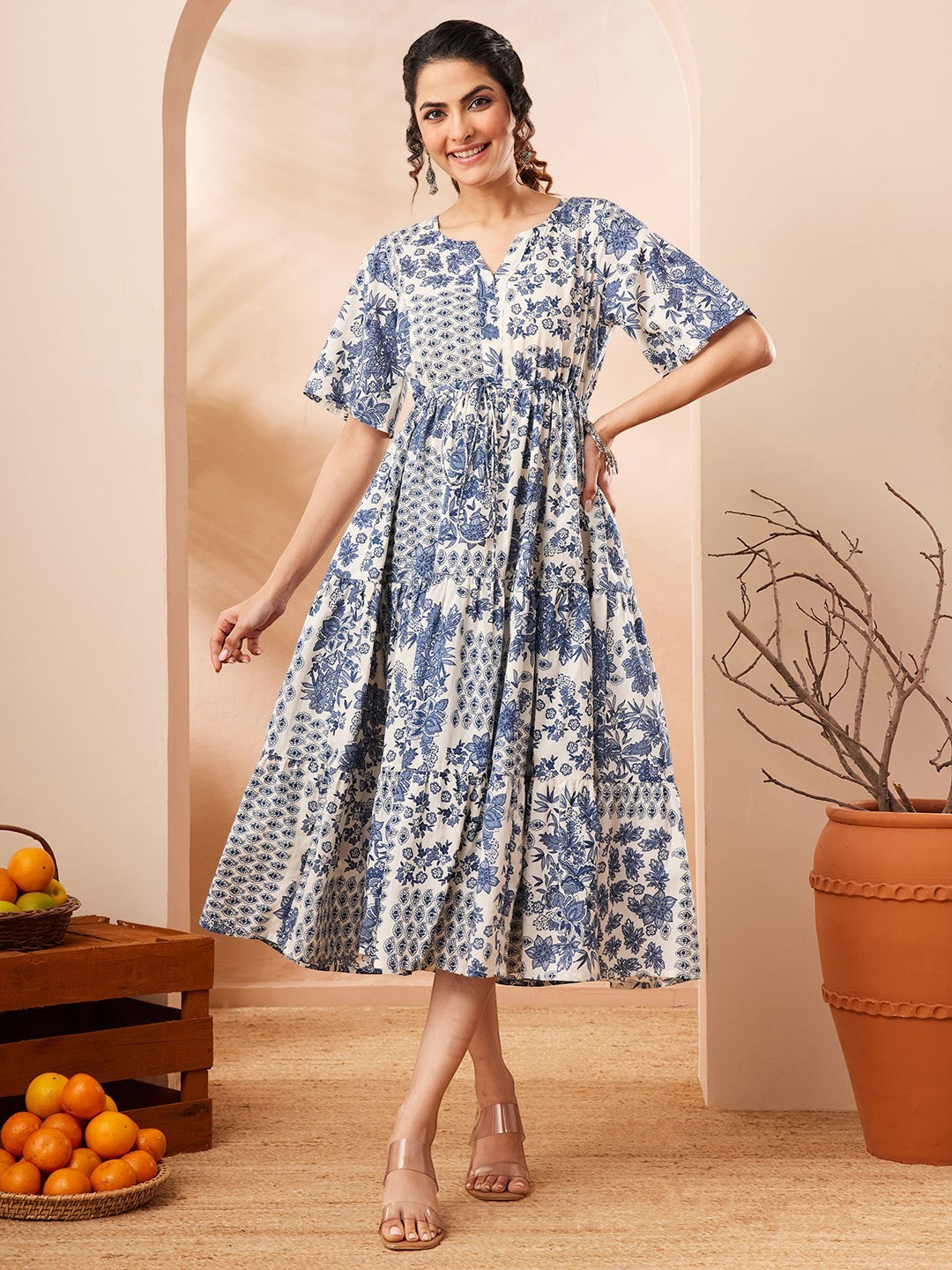 Naanu blue and white floral patchwork tiered midi dress with flutter sleeves and notched V-neckline.