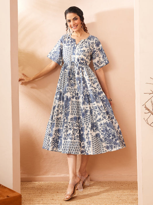 Naanu blue and white floral patchwork tiered midi dress with flutter sleeves and notched V-neckline.