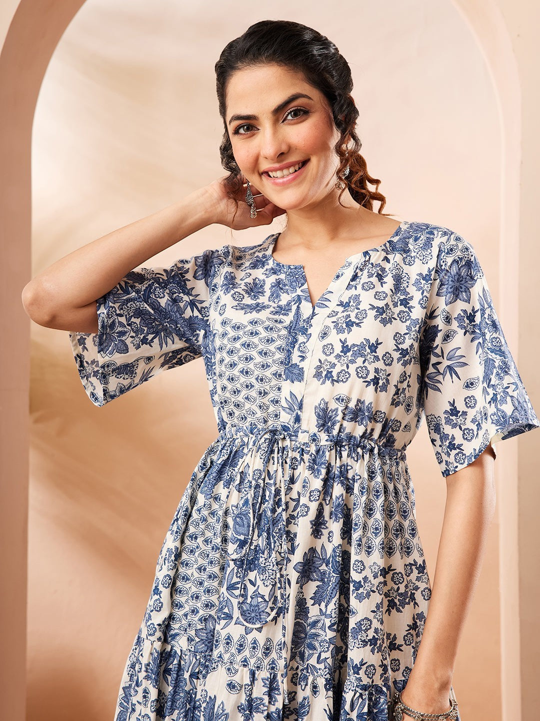 Naanu blue and white floral patchwork tiered midi dress with notched V-neck and flutter sleeves.