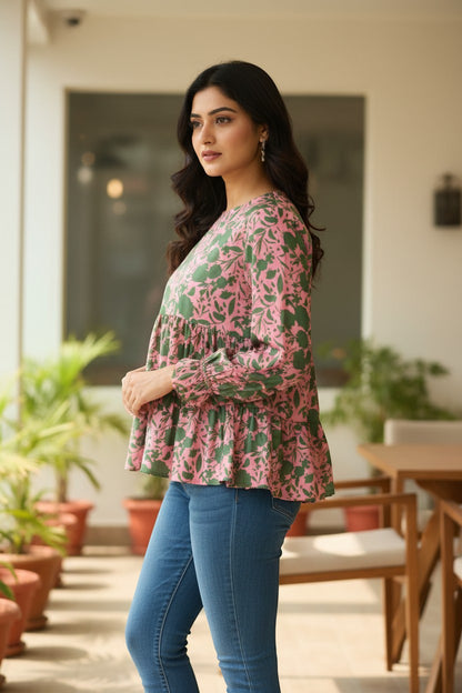 Naanu blush pink satin peplum top with green botanical print, tiered ruffle hem, and full sleeves.