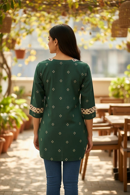 Naanu bottle green cotton kurti with geometric diamond motifs and ikat border trim on neckline and cuffs.