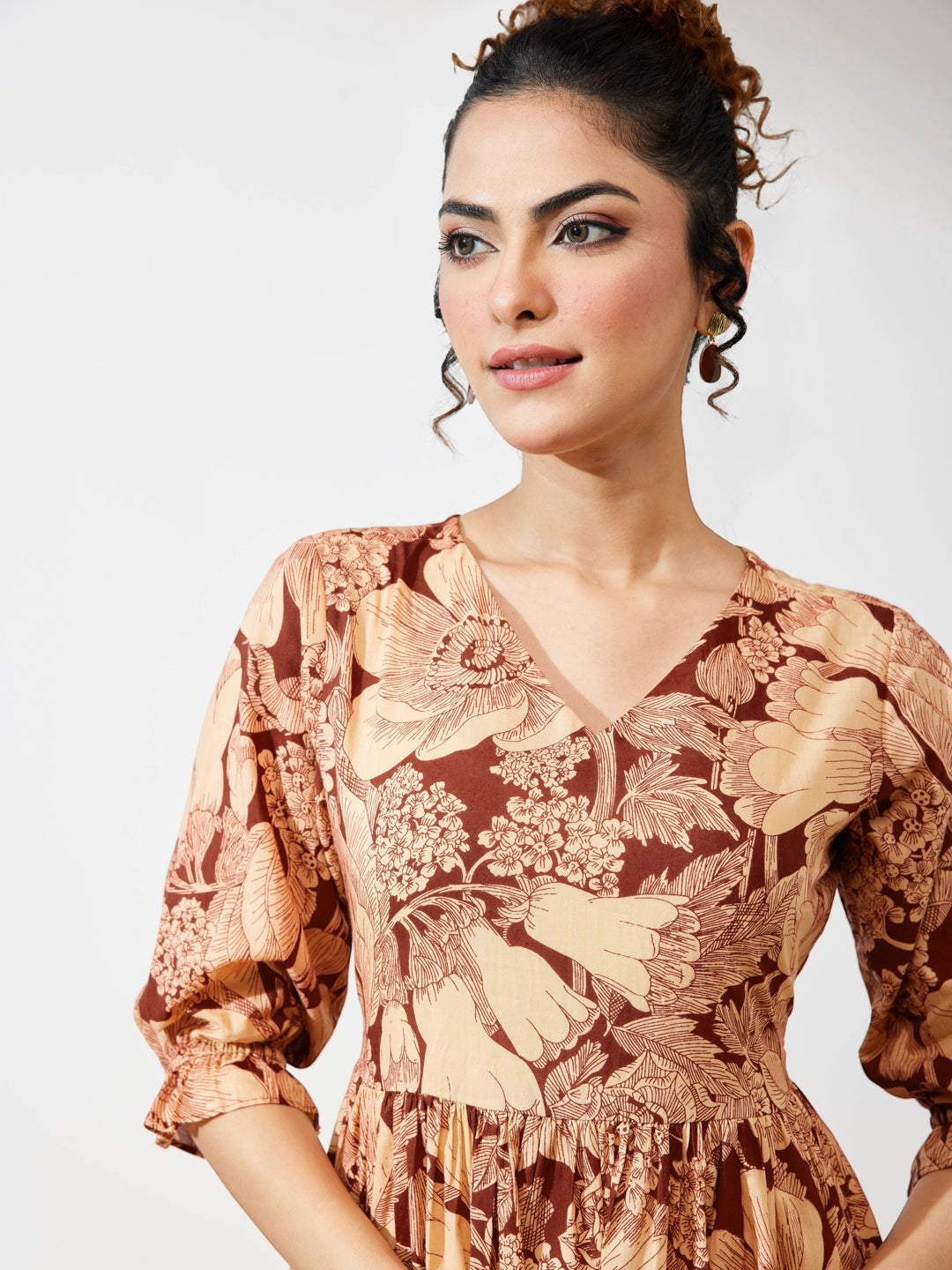 Naanu brown floral midi dress with V-neck, puff sleeves, and tiered skirt. Botanical print in cream and peach.