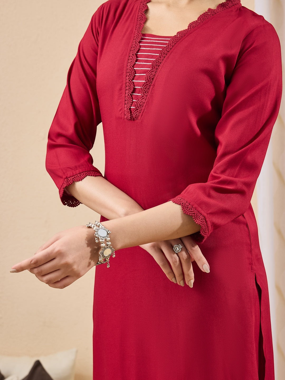 Naanu crimson red straight kurta with lace trim neckline and sleeves, paired with slim pants and printed dupatta.