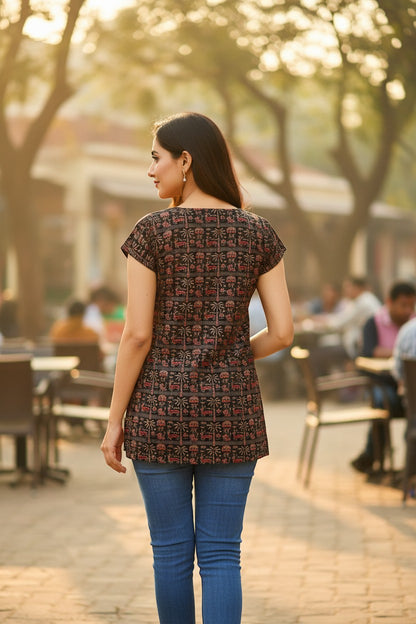 Naanu dark brown cotton top with Warli tribal print, V-neck, and cap sleeves, worn by a woman.