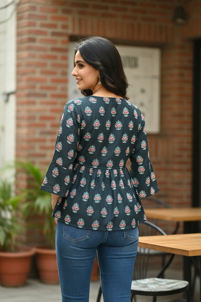 Naanu dark charcoal teal peplum top with pink and white floral block print and flared bell sleeves, worn by a model with blue jeans.