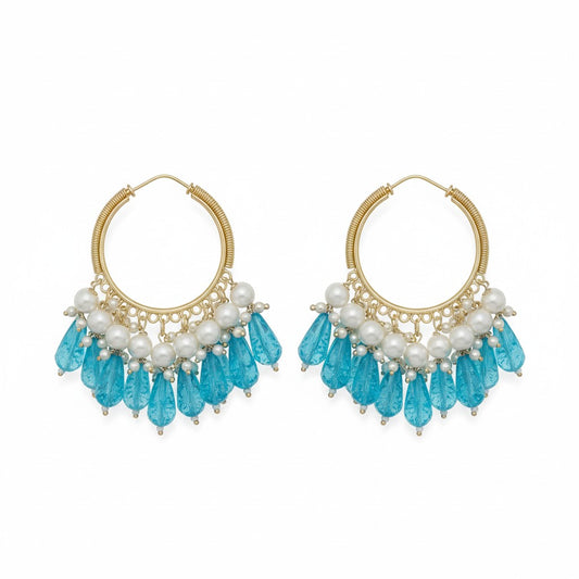 Naanu gold hoop earrings with pearl and blue crystal drops. Features gold wire-wrapped hoops with pearl clusters and faceted blue teardrop beads.