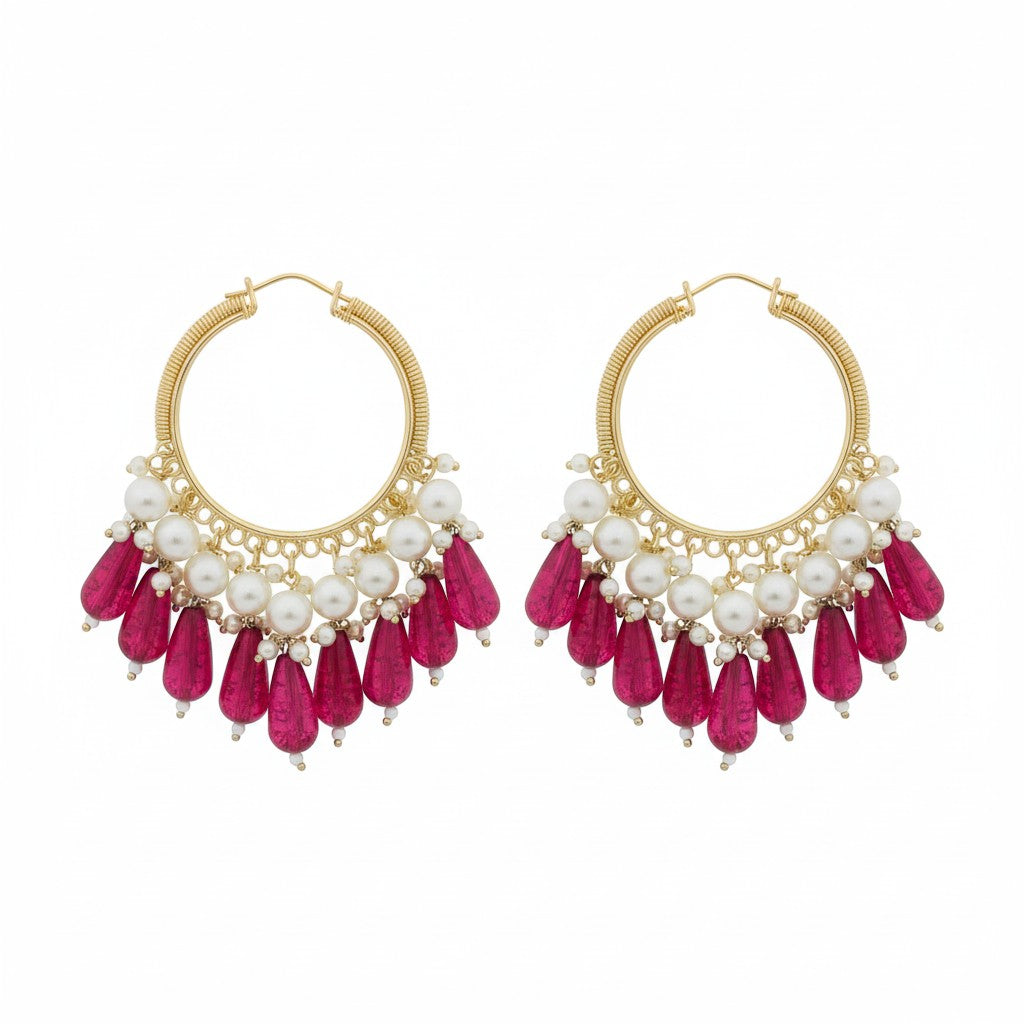 Naanu gold hoop earrings with pearl clusters and deep pink crystal teardrop drops. Wire-wrapped coil hoop design.