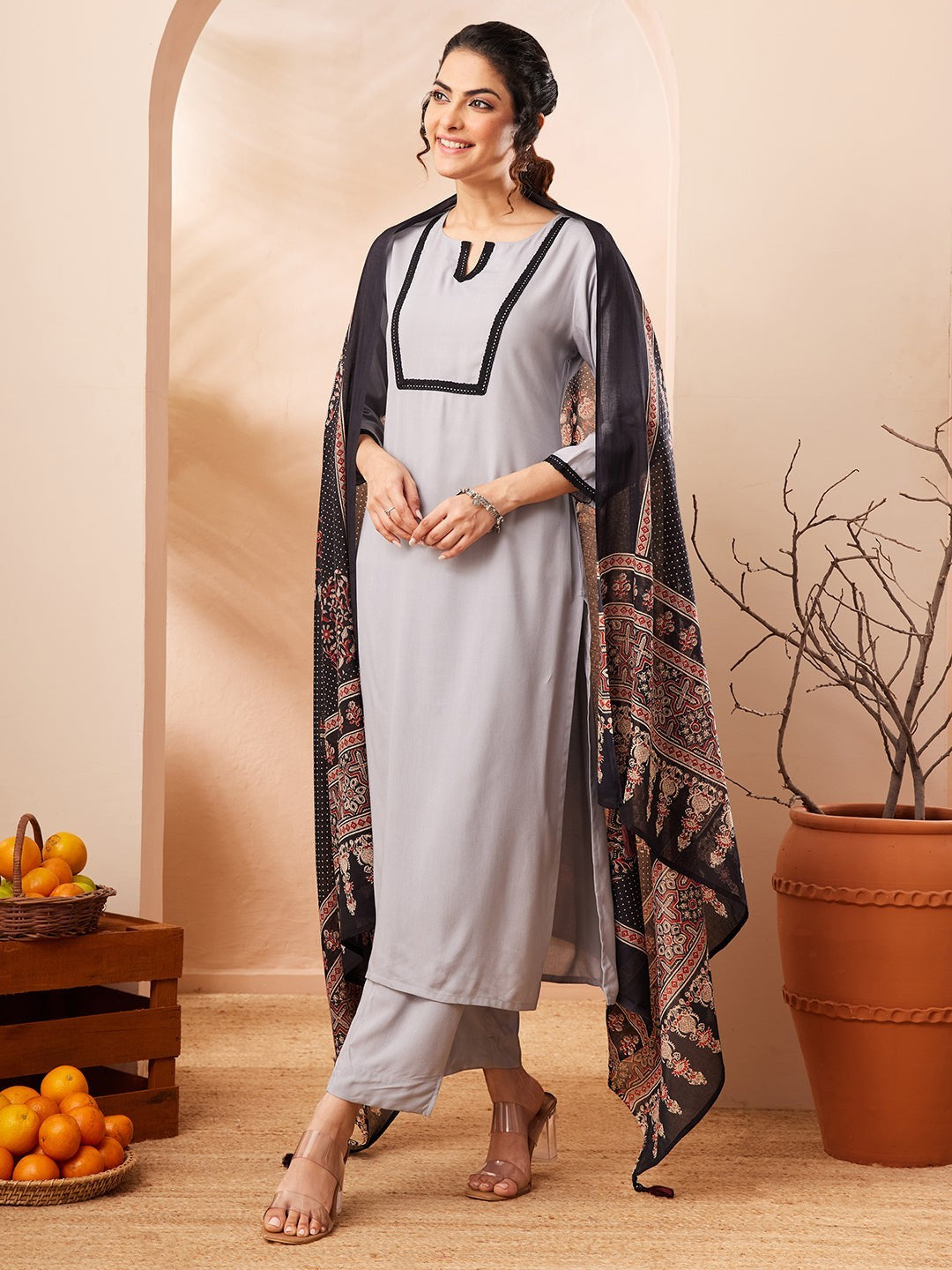 Naanu grey rayon straight kurta set with black contrast border and embellished neckline, paired with matching pants and a black printed dupatta.