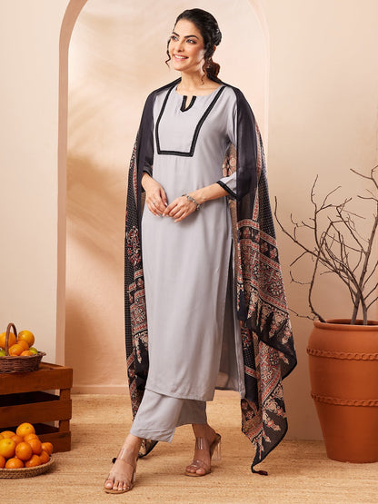 Naanu grey rayon straight kurta set with black contrast border and embellished neckline, paired with matching pants and a black printed dupatta.