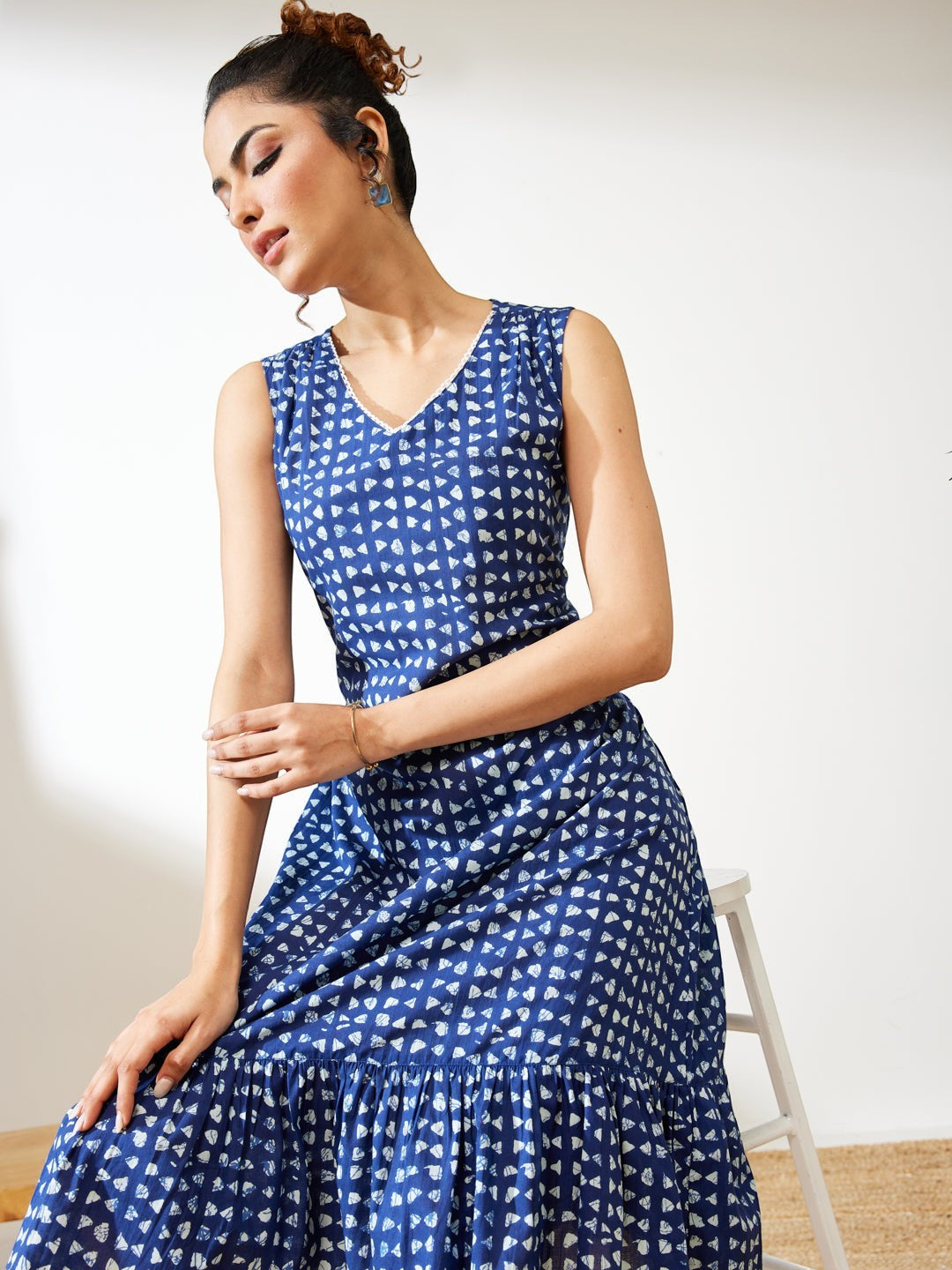 Naanu indigo blue block print tiered midi dress with V-neck and lace trim. Sleeveless ethnic fusion wear.