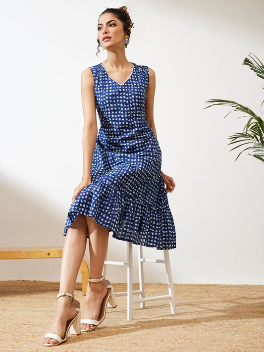 Naanu indigo blue block print tiered midi dress with V-neck and tie-back waist. Sleeveless ethnic fusion wear.