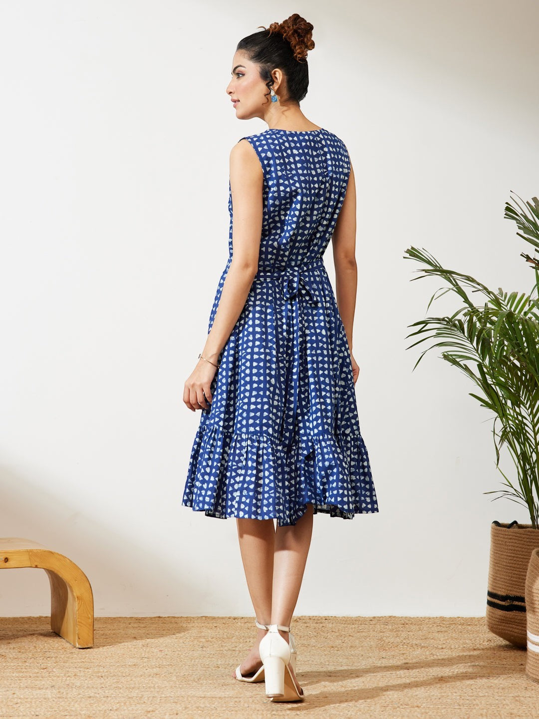 Naanu Indigo blue block print tiered midi dress with V-neck and tie-back waist. Sleeveless with structured shoulders and ruffle hem.