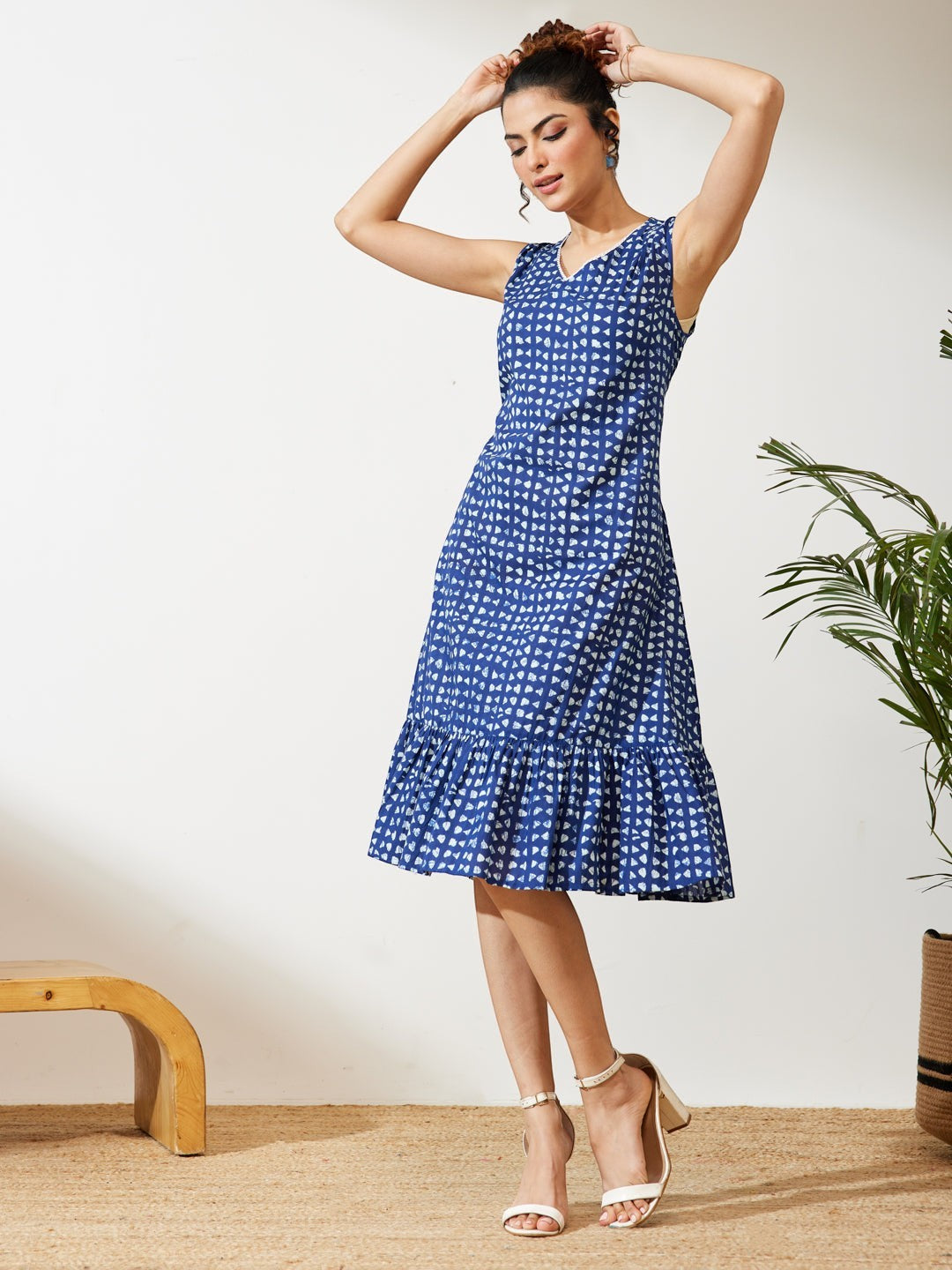 Naanu indigo blue block print tiered midi dress with V-neck and ruffle hem. Sleeveless ethnic fusion wear.