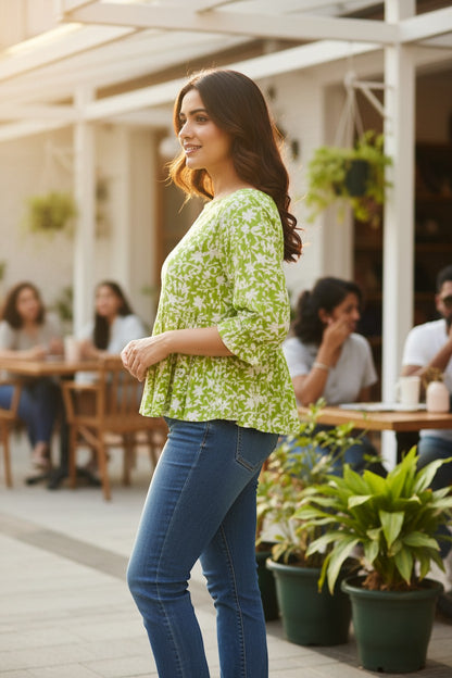 Naanu lime green and white floral print 3/4 sleeve peplum top made of 100% cotton, featuring a boat neckline and ruffle cuffs.