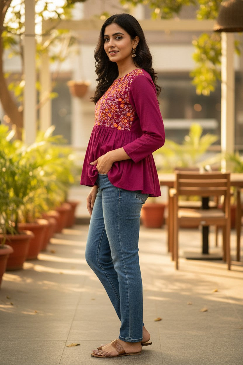 Naanu magenta cotton peplum top with full sleeves and vibrant floral embroidery on the yoke. Round neck, empire waist, and gathered peplum skirt.