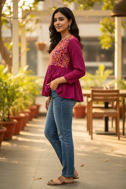 Naanu magenta cotton peplum top with full sleeves and vibrant floral embroidery on the yoke. Round neck, empire waist, and gathered peplum skirt.