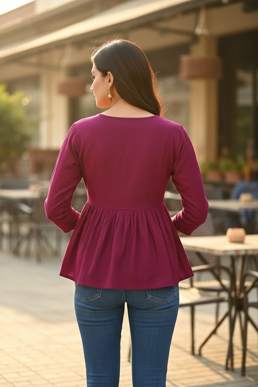 Naanu deep magenta cotton peplum top with full sleeves and floral embroidered yoke. Model wears blue jeans.