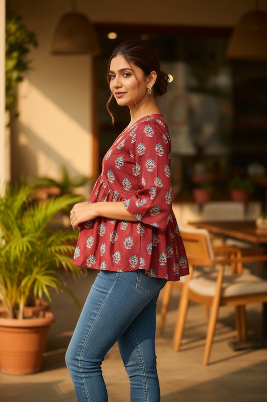 Naanu maroon cotton peplum top with bell sleeves and scattered blue floral block print. Model wears jeans.