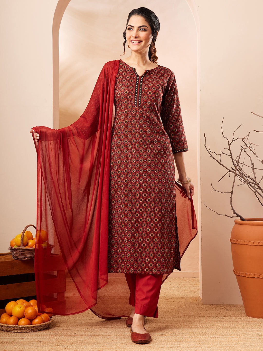 Naanu maroon cotton kurta with Ajrakh diamond print, keyhole neckline, and embroidered cuffs, paired with slim pants and crimson chiffon dupatta.