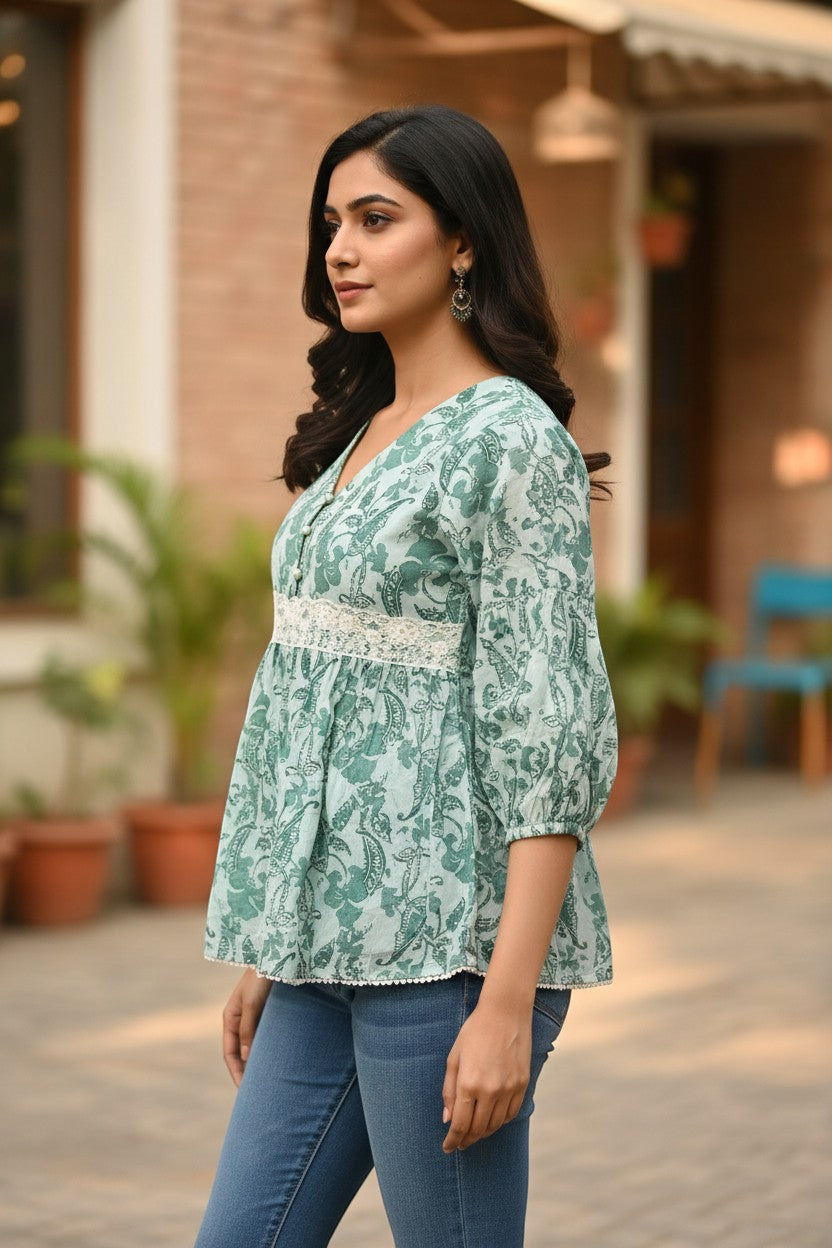 Naanu mint green cotton peplum top with teal botanical print, V-neck, bishop sleeves, and white lace trim.