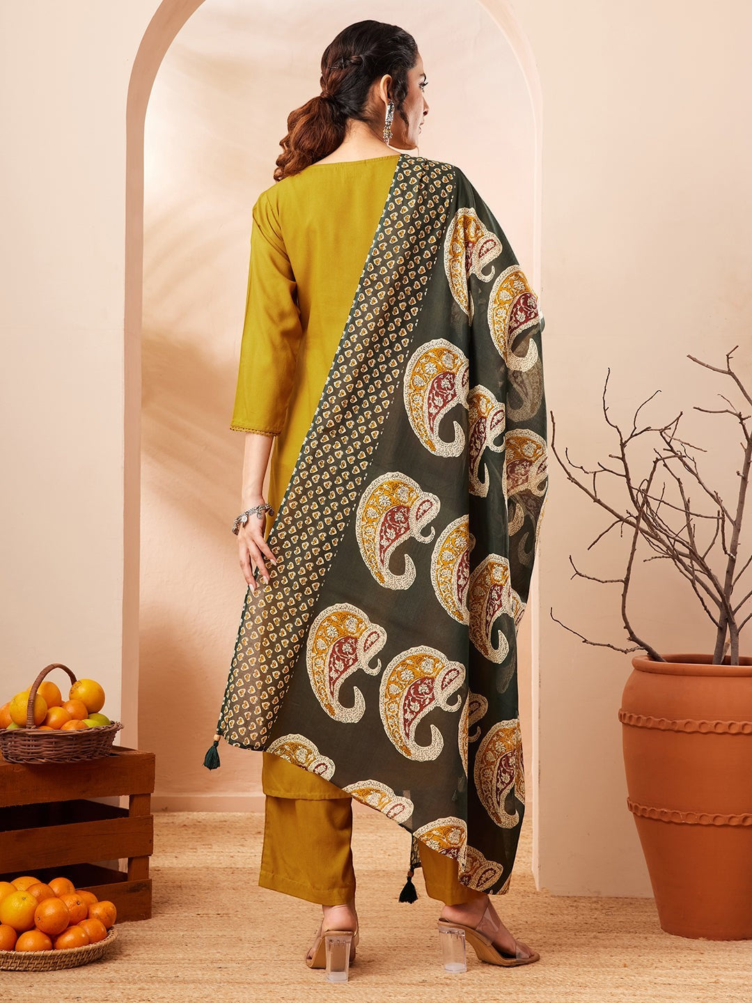 Naanu mustard yellow solid straight kurta with gold trim, palazzo pants, and a forest green paisley print dupatta with tassel ends.