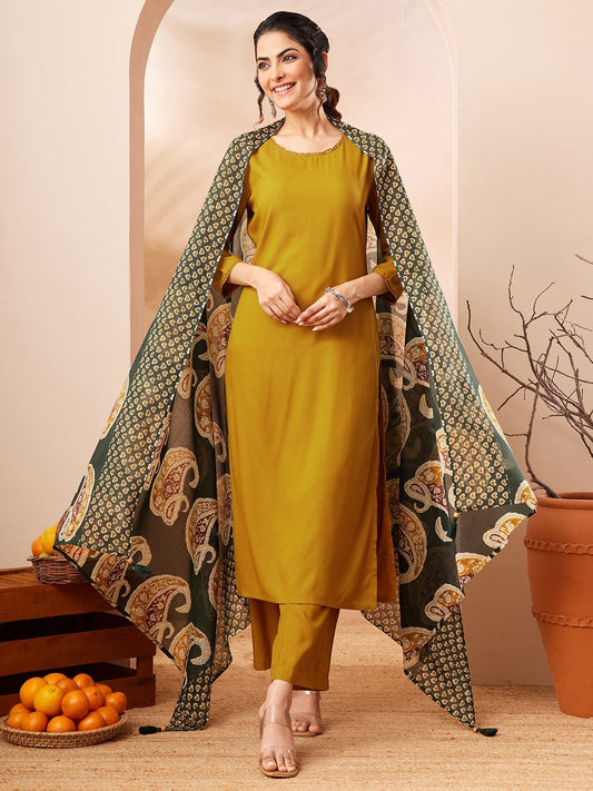Naanu mustard yellow solid straight kurta with gold trim, palazzo pants, and a forest green paisley dupatta.