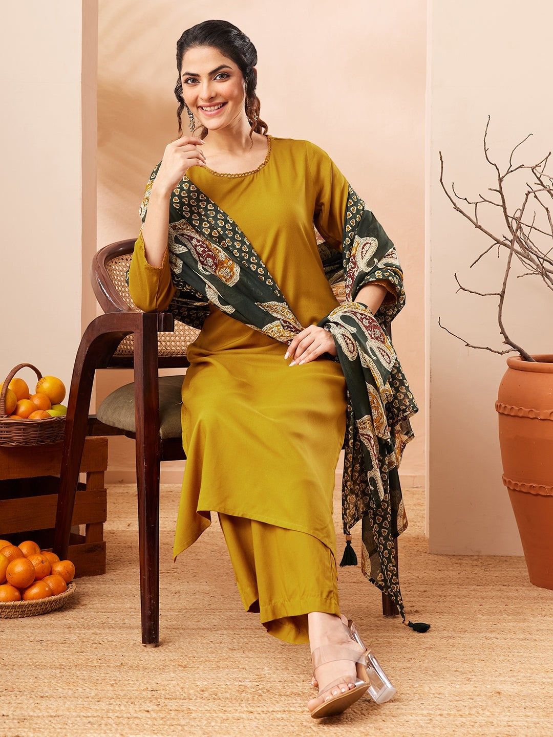 Naanu mustard yellow solid straight kurta with gold trim, palazzo pants, and a forest green paisley dupatta with tassel ends.