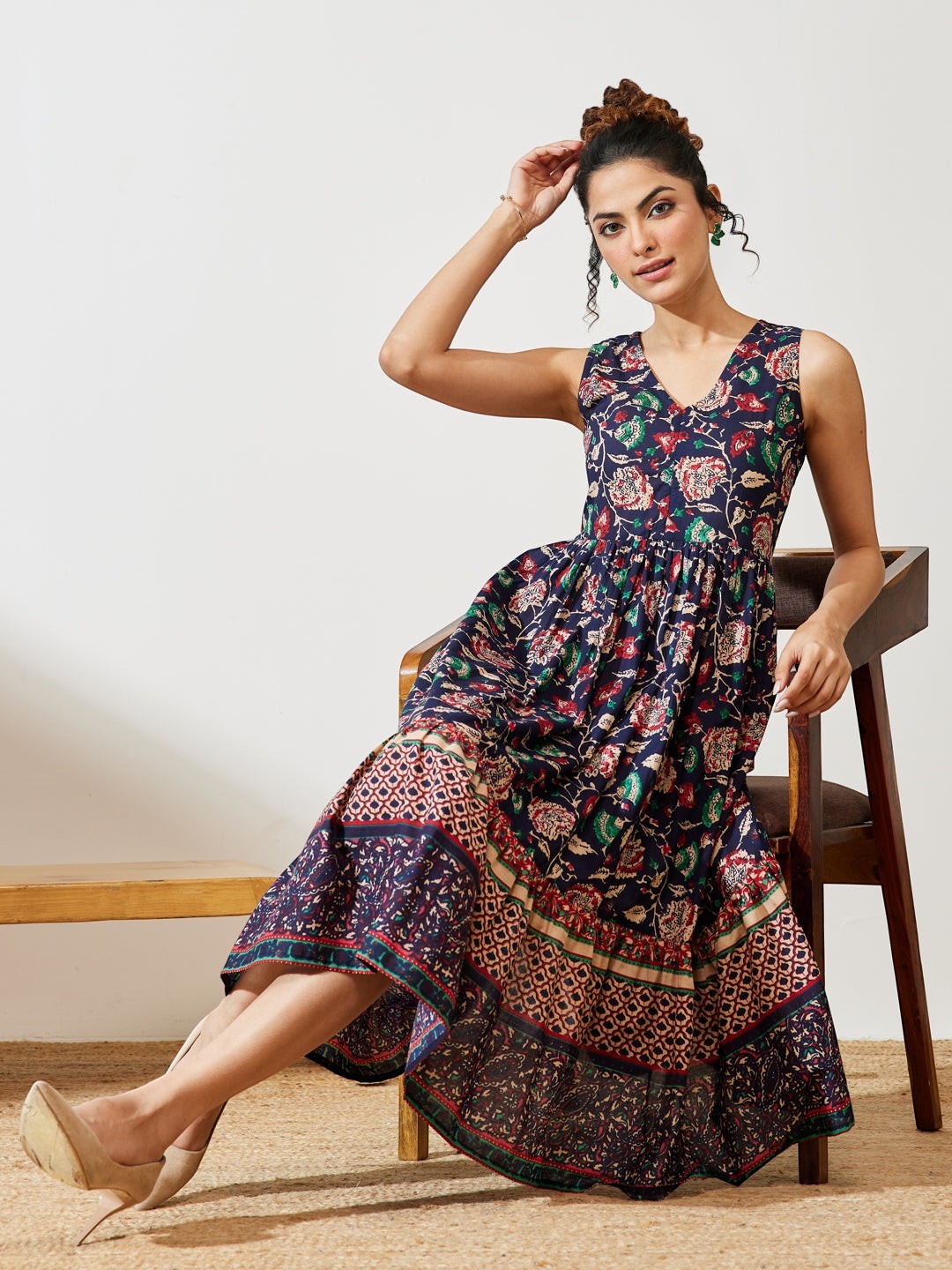 Naanu navy blue cotton midi dress with V-neck, empire waist, and tiered floral border hem. Sleeveless design.