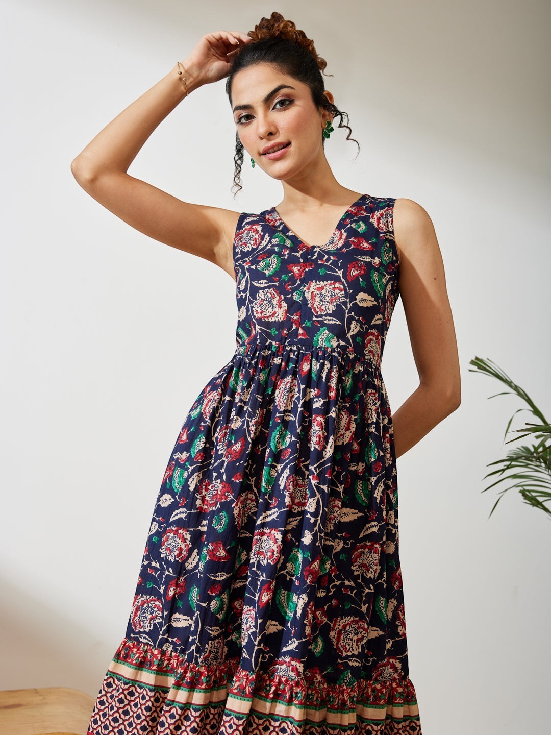 Naanu navy cotton midi dress with V-neck, empire waist, and tiered border hem featuring a Kalamkari floral print in red, teal, and ivory.