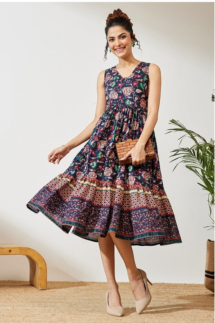 Naanu navy cotton midi dress with V-neck, empire waist, and tiered floral border hem. Sleeveless design with deep side pockets.
