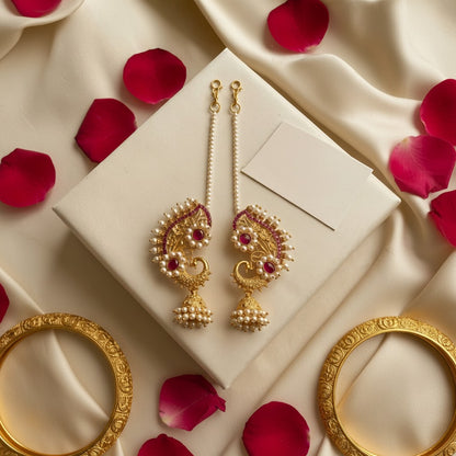 Naanu gold paisley temple earrings with ruby kemp stones, seed pearls, and pearl jhumkas, connected by a pearl chain.