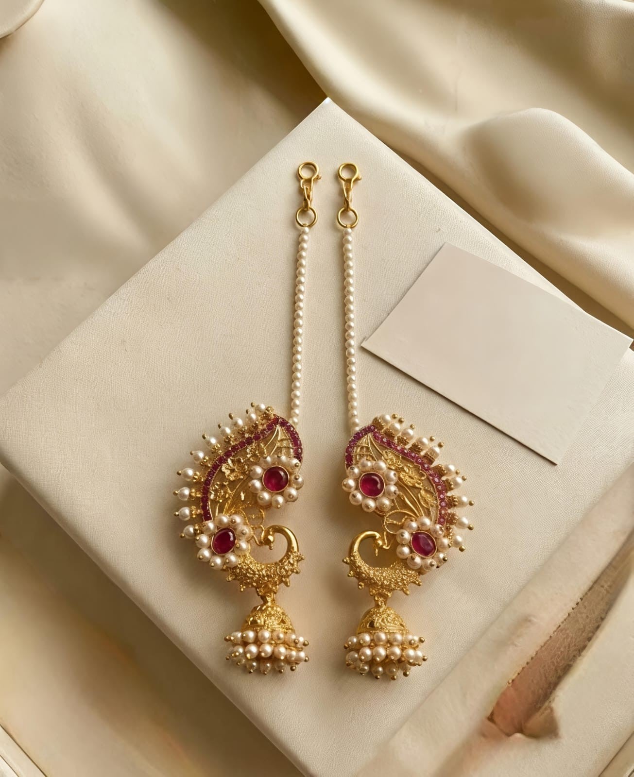 Naanu gold paisley temple earrings with ruby kemp, pearl jhumka, and pearl chain connector. Traditional bridal jewellery.