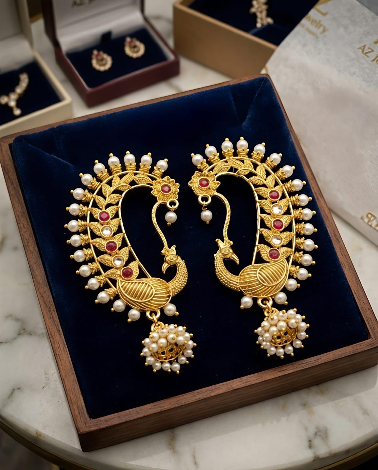 Naanu gold peacock chand bali temple earrings with pearl cluster jhumka, red kemp stones, and kundan accent.