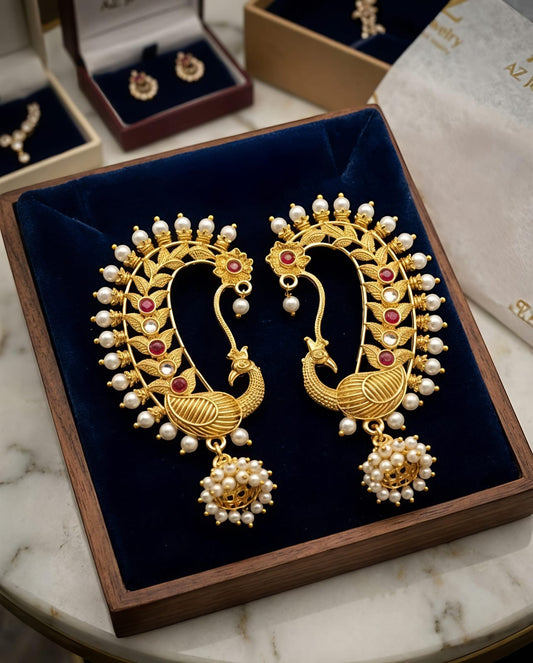 Naanu gold peacock chand bali temple earrings with pearl cluster jhumka, red kemp stones, and kundan accent.