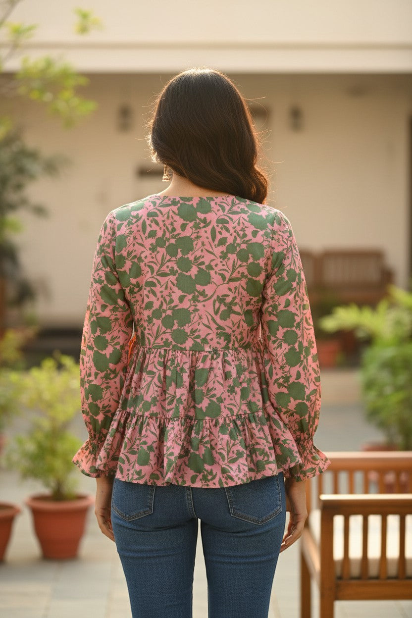 Naanu blush pink satin peplum top with green botanical print, tiered ruffle hem, and full sleeves.