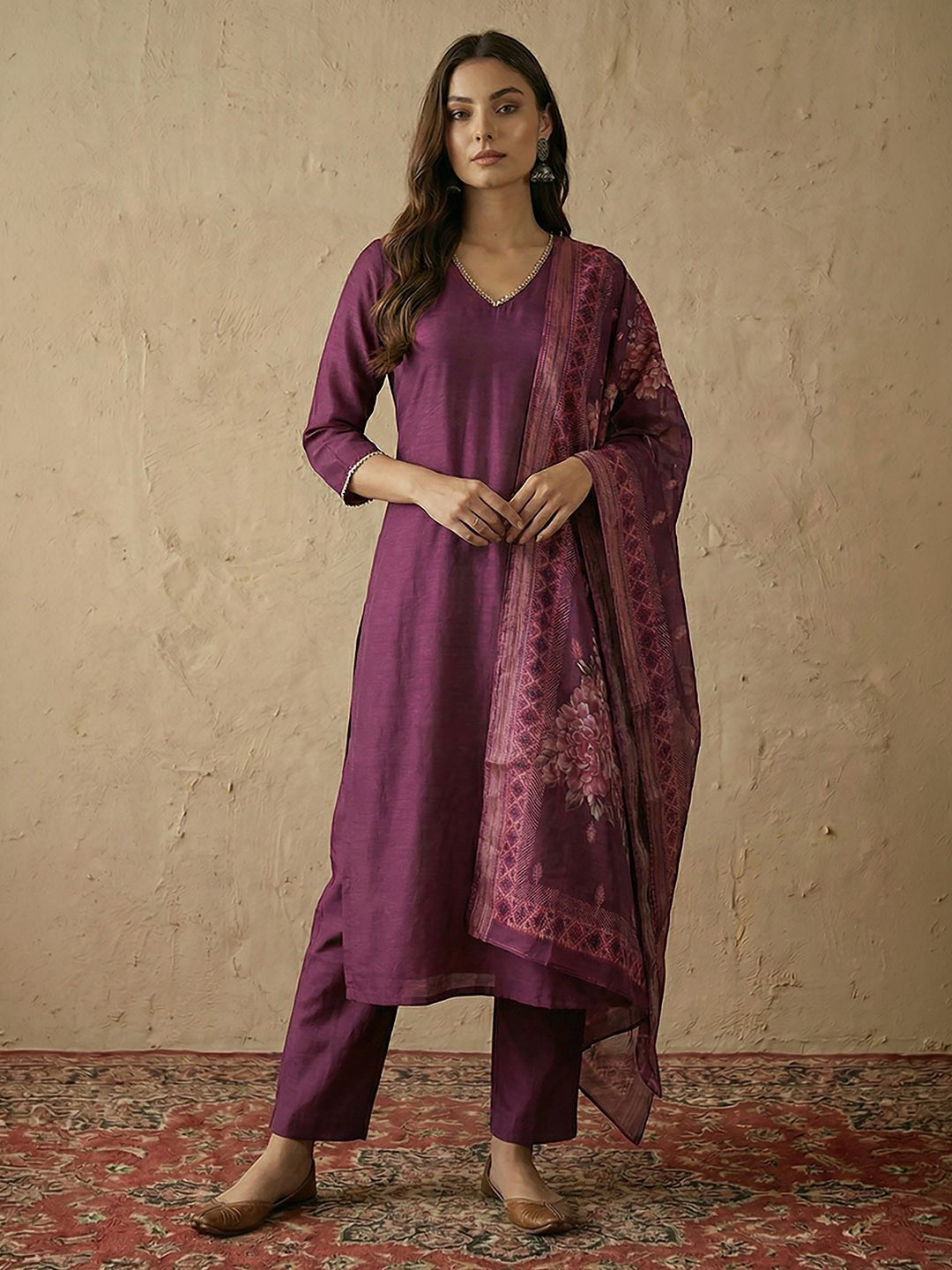Naanu plum silk blend straight kurta set with V-neck, silver lace trim, and floral organza dupatta. Model is wearing matching pants and flats.
