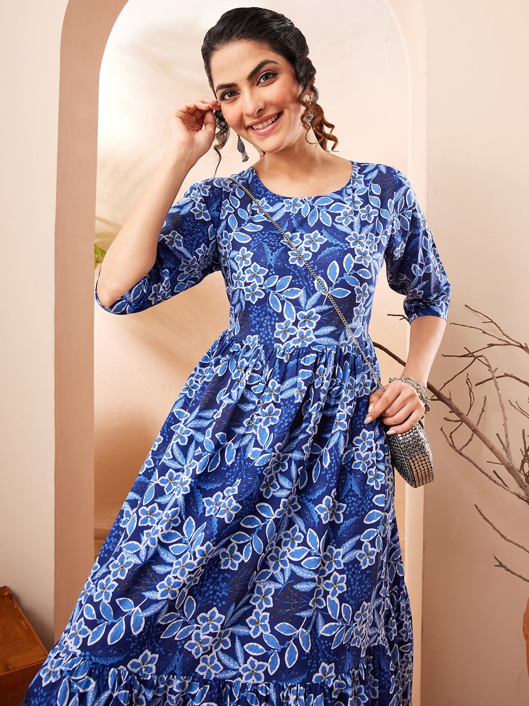Naanu royal blue floral print midi dress with 3/4 sleeves and tiered skirt. Model wears it with a silver bag.