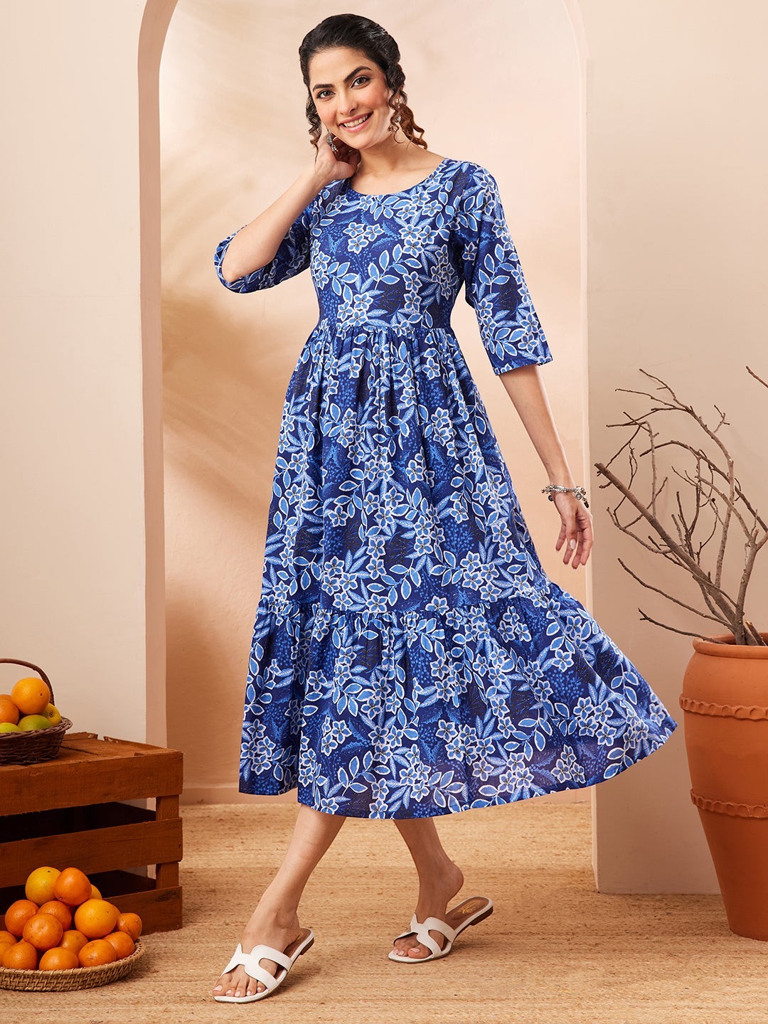 Naanu royal blue floral print midi dress with 3/4 sleeves and tiered skirt. Model is wearing white sandals.
