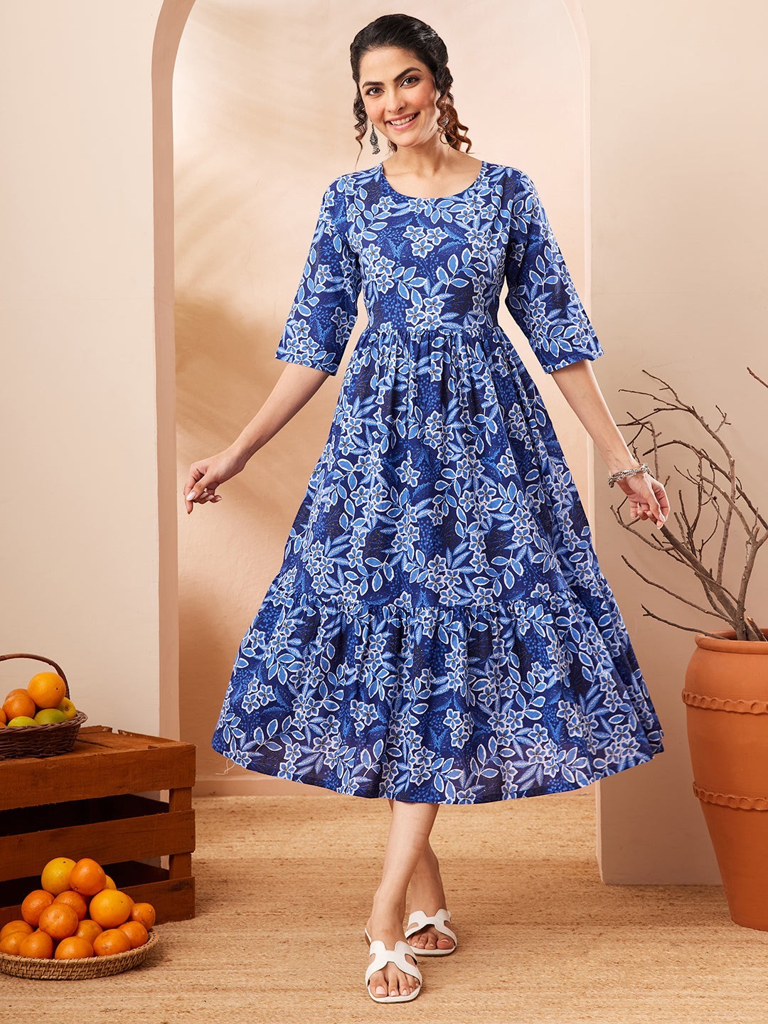 Naanu royal blue floral print midi dress with tiered skirt and 3/4 sleeves, worn by a woman.
