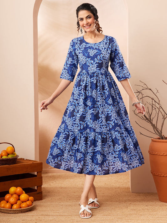 Naanu royal blue floral print midi dress with tiered skirt and 3/4 sleeves, worn by a woman.